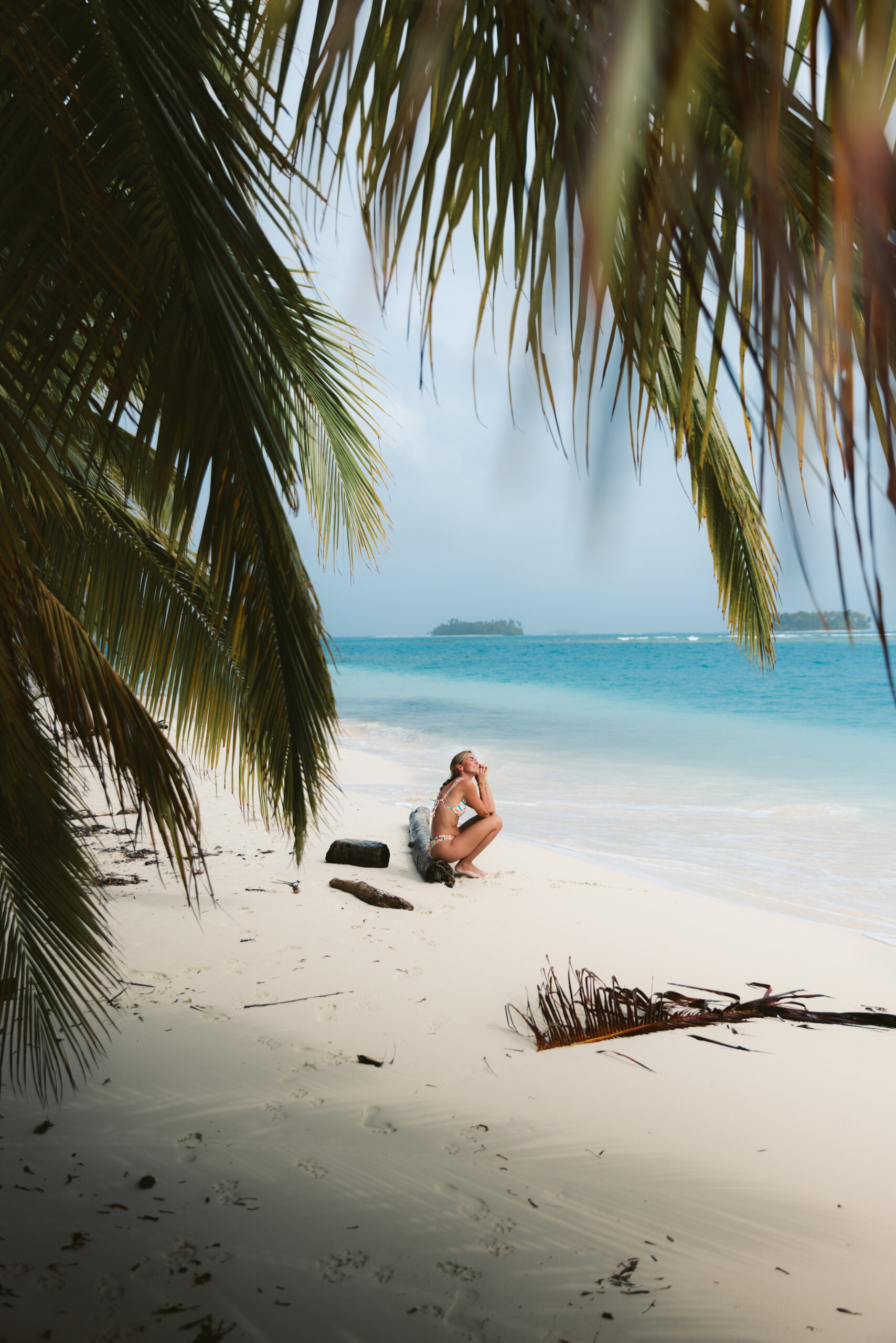 A young woman relaxes on the pristine beaches of San Blas Islands, Panama, surrounded by soft white sand and turquoise waters. With the sun shining down, she embraces the tranquility and beauty of this tropical paradise. Every moment spent here with Nomad Sailors is a chance to create unforgettable memories in an idyllic setting.